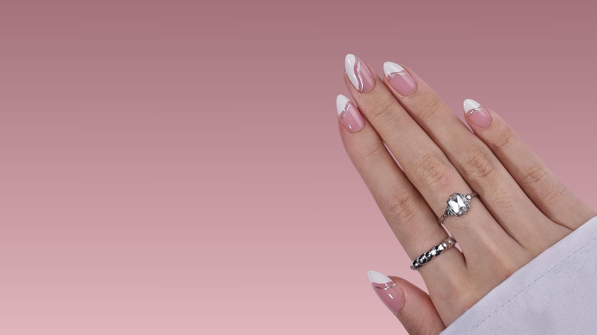 Mandelförmige Press-on-Nägel in Rosa und Weiß mit modernem French Design und Silberdetails an einer Hand
