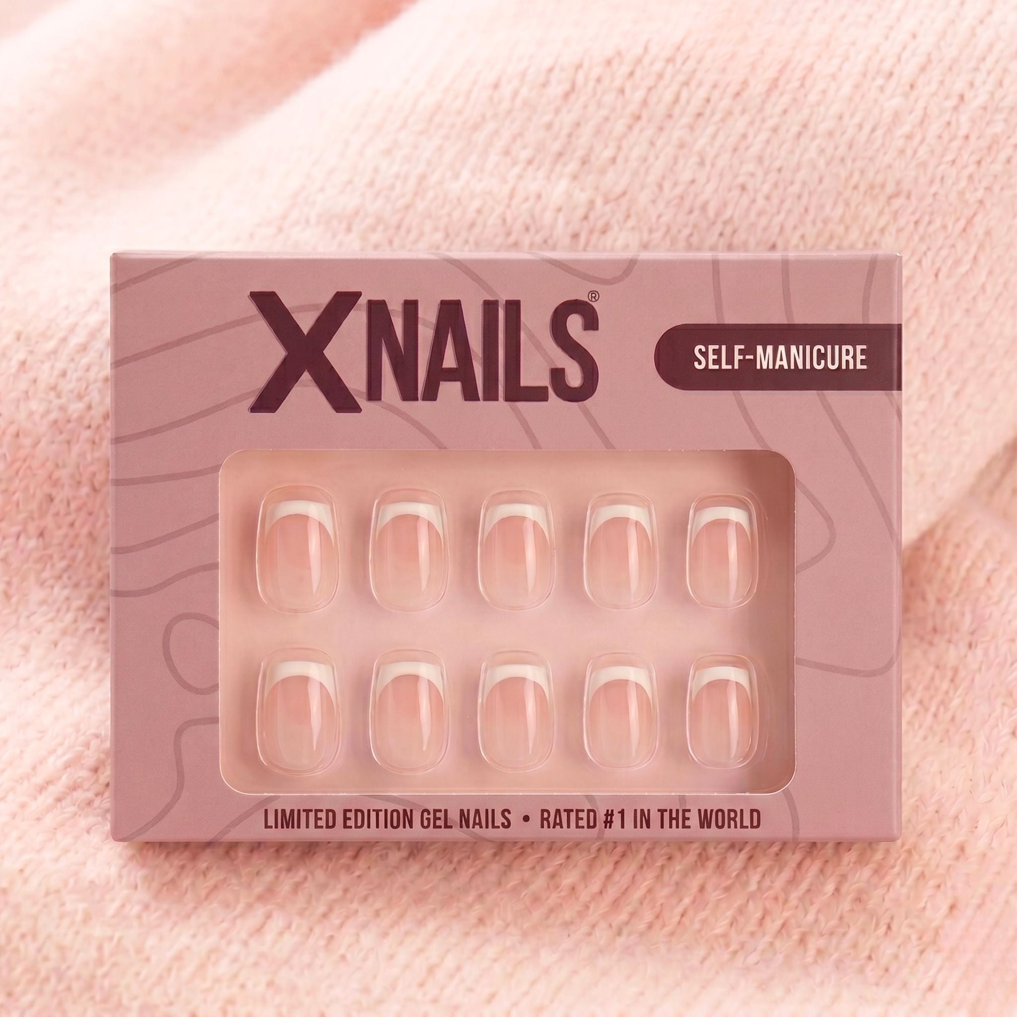 XNails-æske med hvide franske korte firkantede press-on negle mod lyserød strikket baggrund