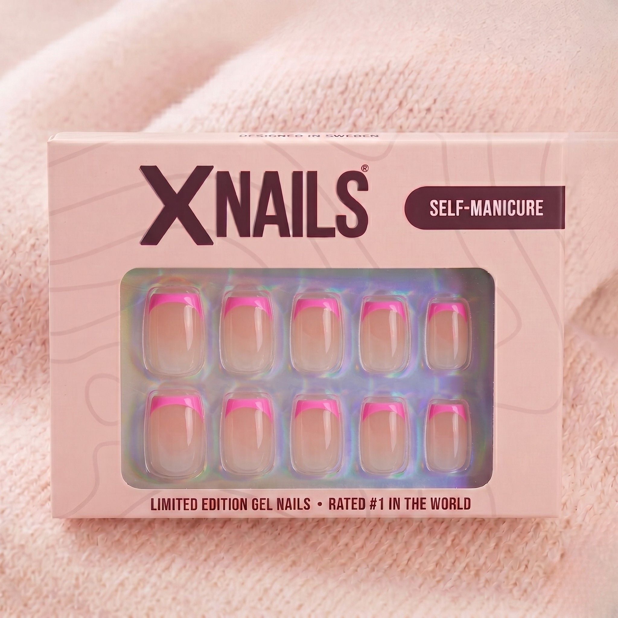 XNails-æske med lyserøde franske korte firkantede press-on negle mod lyserød strikket baggrund