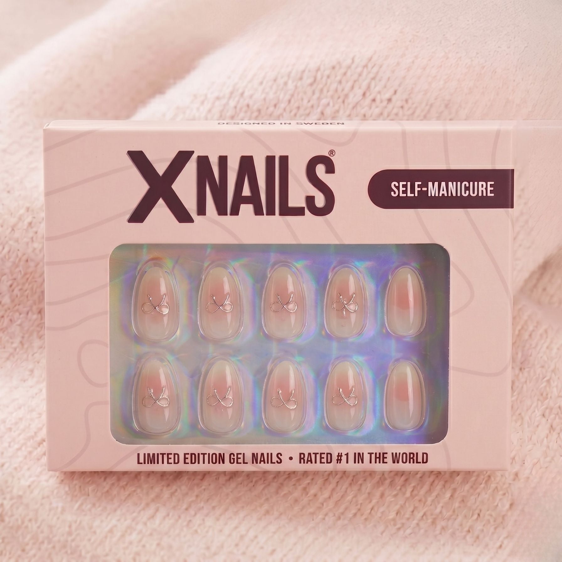 Aura Amoré mandelförmige Press-on-Nägel mit weiß-rosa Ombré und Silberösen, in rosa XNails Verpackung für Maniküre