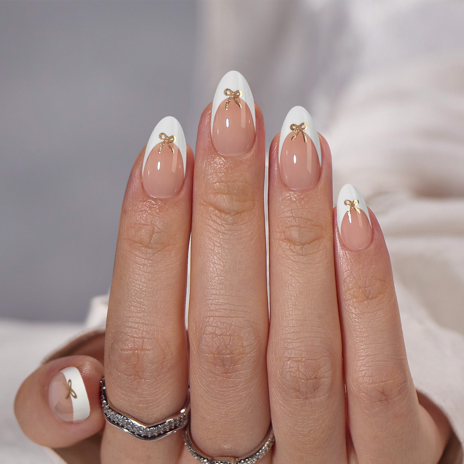 Vita French press-on naglar med guldrosett – mandelform på hand med silverring XNails