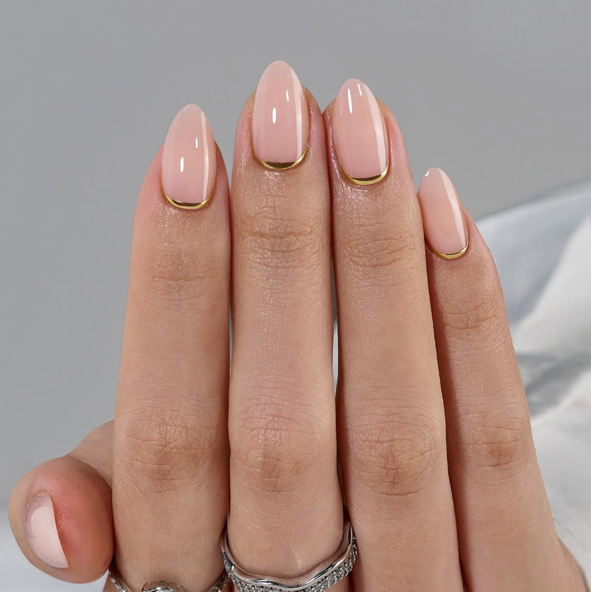 Golden Glimmer Press-on-Nägel Nahaufnahme, nudefarbene Basis und Goldlinie entlang der Nagelhaut