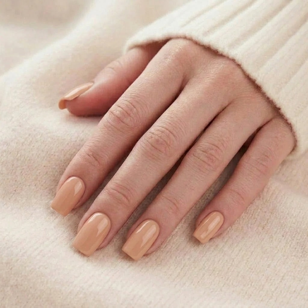 Honey Heaven press-on naglar i solid nude/honey-ton på hand mot beige stickad tröja