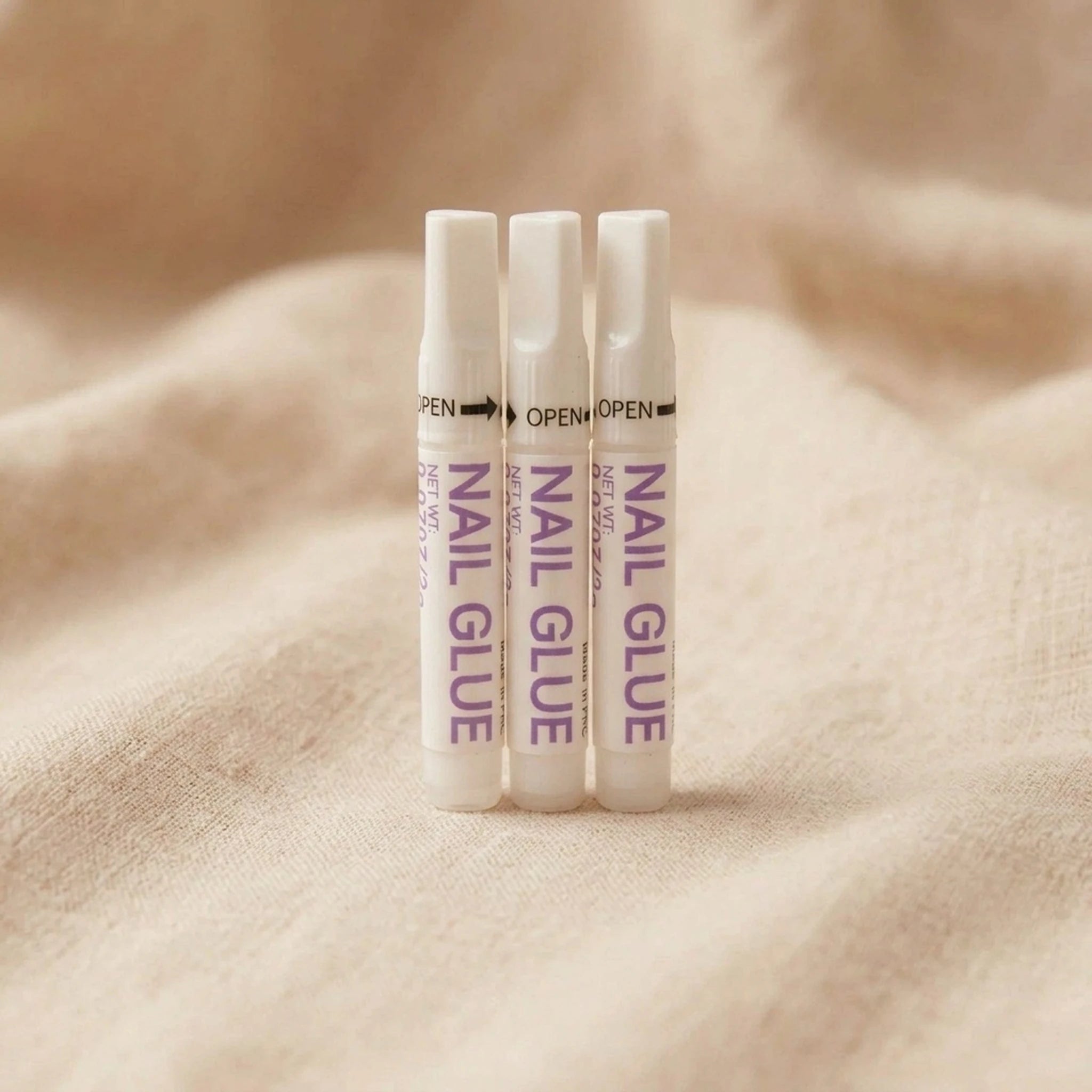 XNails Nail Glue Nagelkleber auf beigem Hintergrund