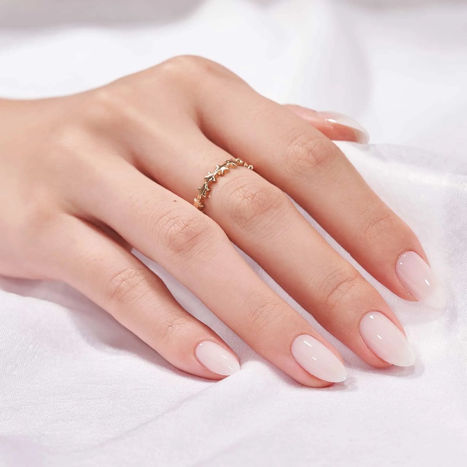 Satin Snow press-on negle styling, nude mandelnegle med guldring mod hvid satin
