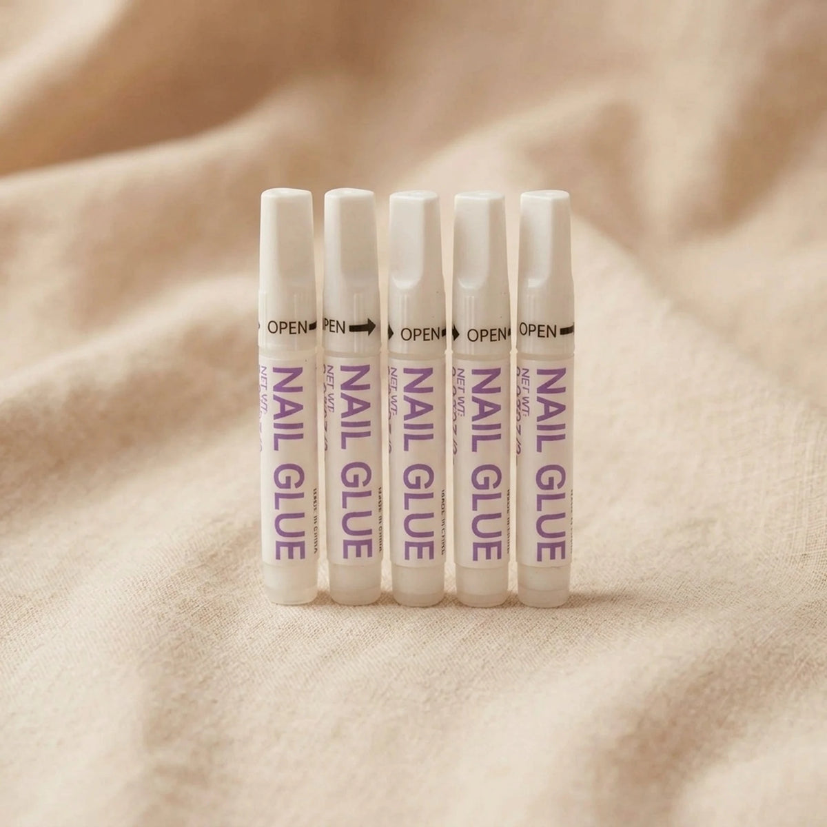 XNails Nail Glue Nagelkleber auf beigem Hintergrund