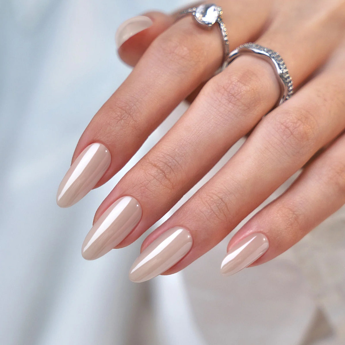 Pearly Perfection Press-on-Nägel Nahaufnahme, Pearl-Mandelform mit Silberring und Kristall vor hellem Hintergrund