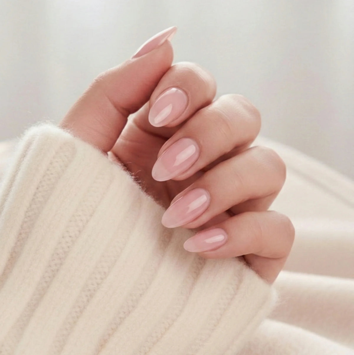 Pinkie Pearl press-on negle sart rosa pearl i mandelform mod creme strikket trøje