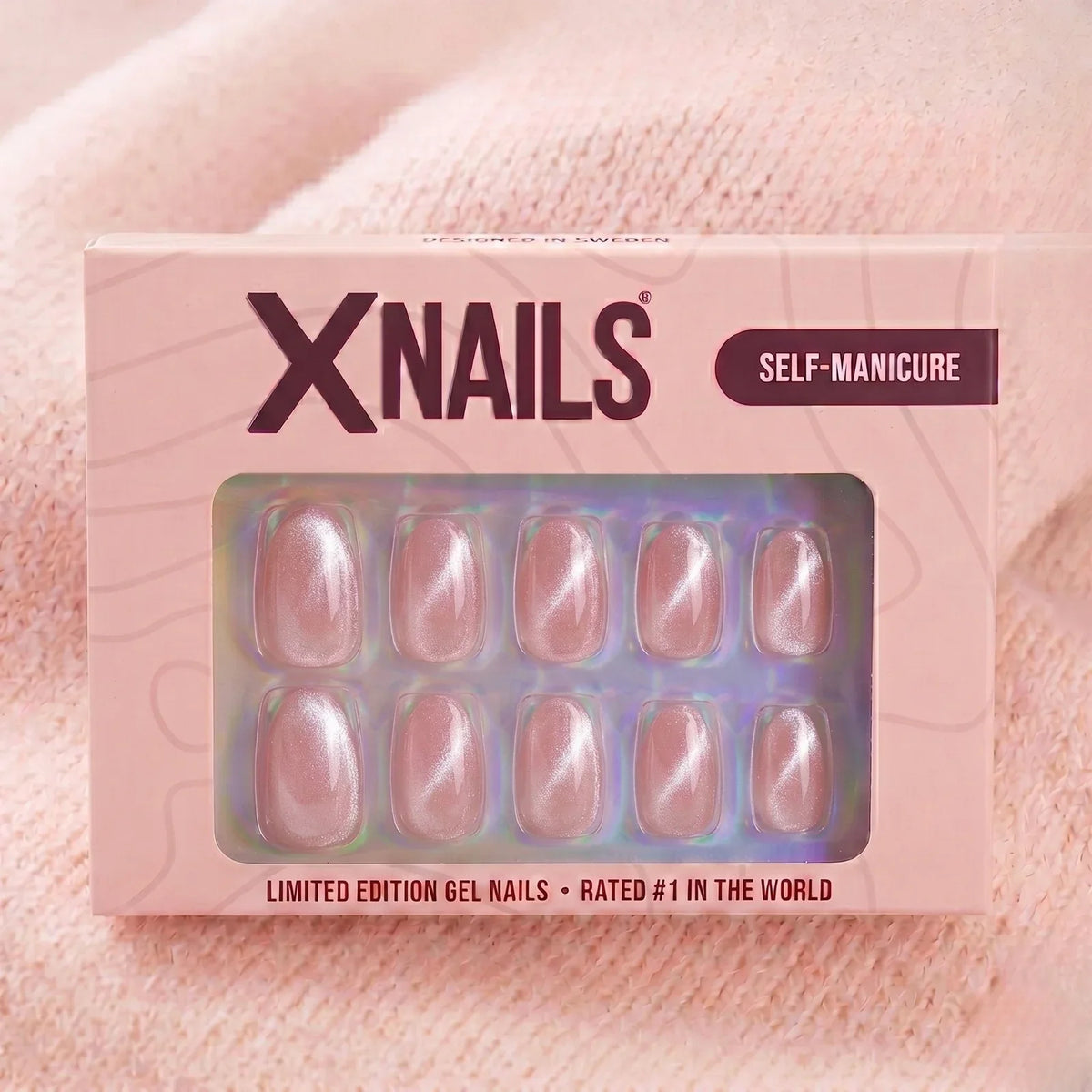 XNails-æske lyserød chrome almond press-on negle mod strikket lyserød baggrund