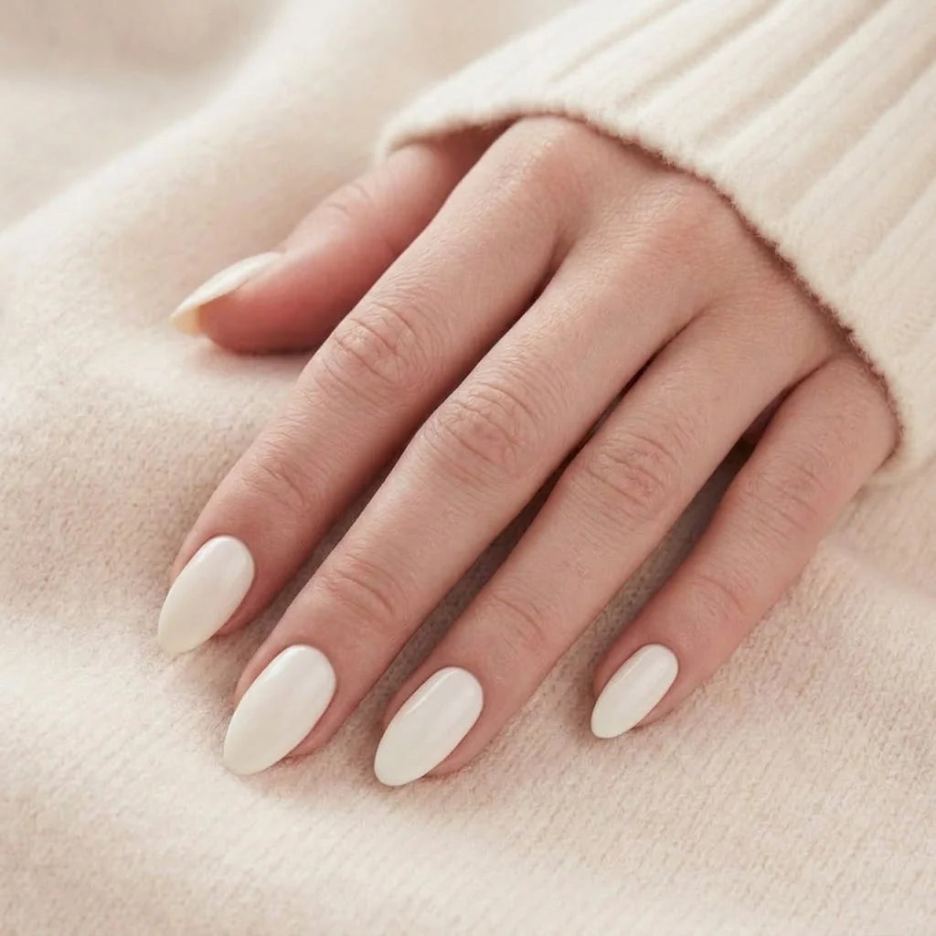 Satin Snow løsnegle nærbillede, cremehvide mandelnegle mod beige cashmere-trøje